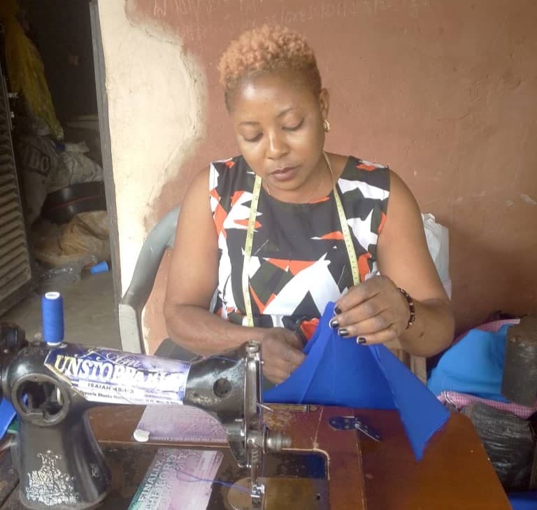 A local tailor working with blue fabric at a sewing machine in her workshop